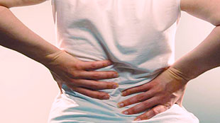 Image of client holding painful lower back